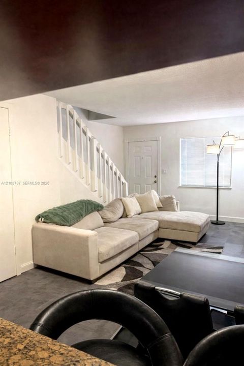 Staircase featuring white balusters and handrail, complemented by neutral tile flooring and a multi-panel entry door