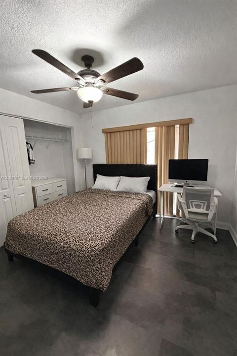 Room featuring tile flooring, ceiling fan with integrated light fixture, closet with paneled doors, and vertical window blinds