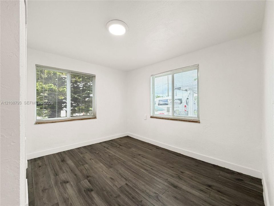 Room featuring wood-finish flooring, two large windows, and a ceiling-mounted light fixture