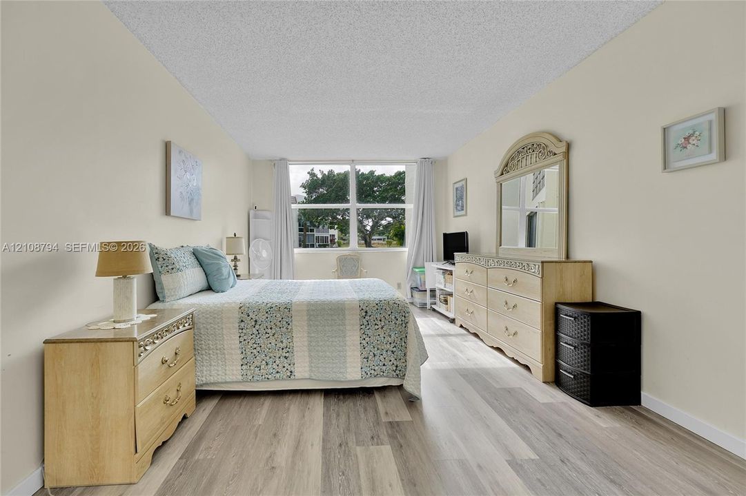 Spacious room featuring wood-finish flooring, a textured ceiling, and a large multi-pane window