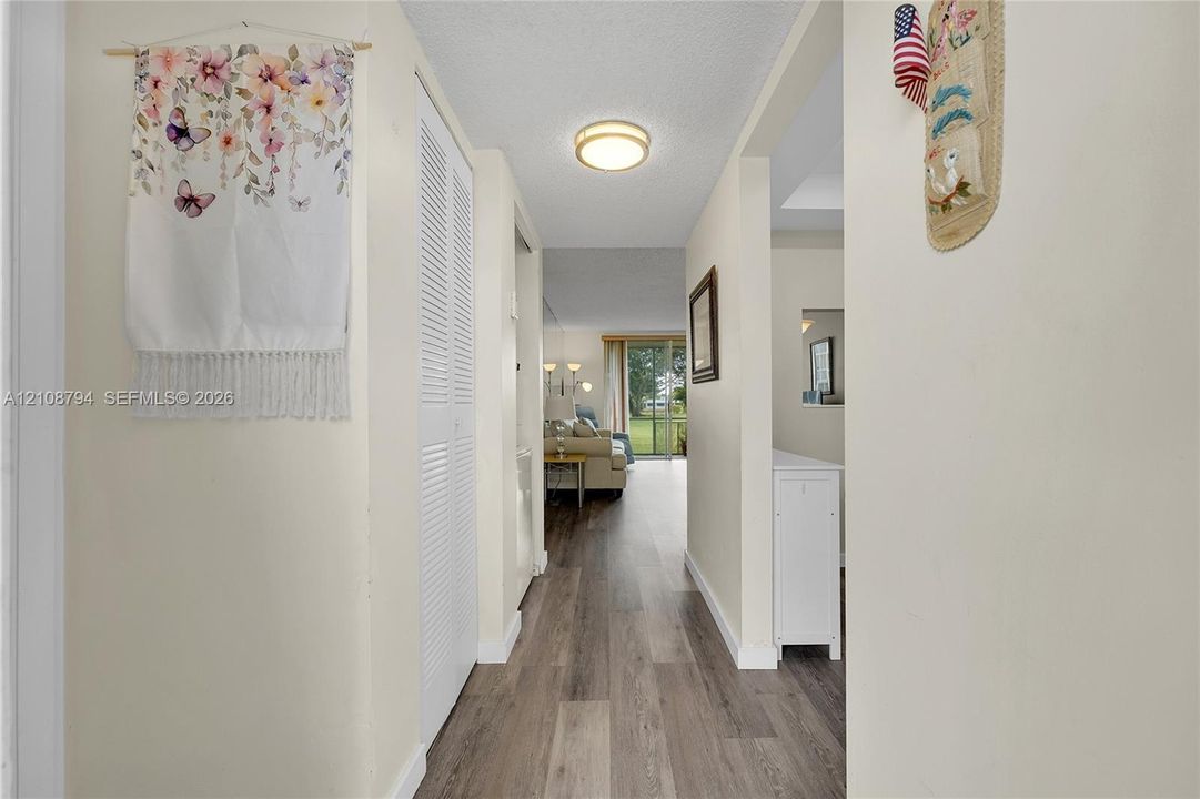 Interior hallway featuring wood-finish flooring, white louvered closet doors, and a flush-mount circular ceiling light fixture