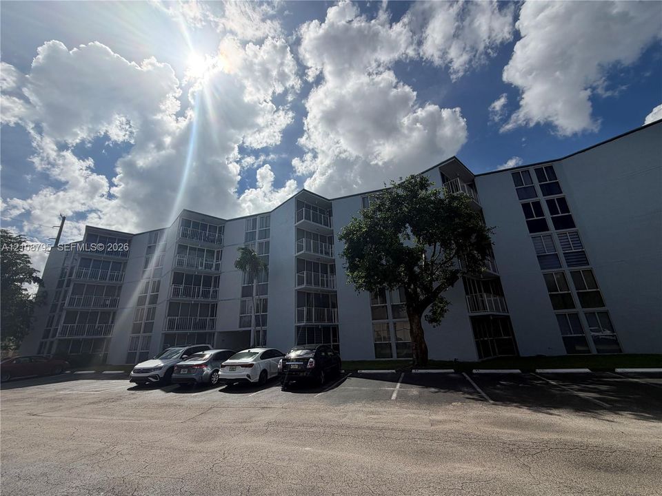 Multi-story building exterior featuring a white facade, private balconies, and glass paneling