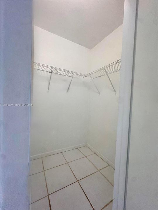 WALKING CLOSET area featuring white tile flooring and wall-mounted wire shelving
