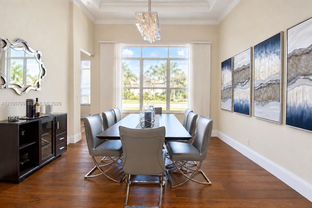 Formal dining area featuring tray ceilings, wood-finish flooring, and a large multi-pane window