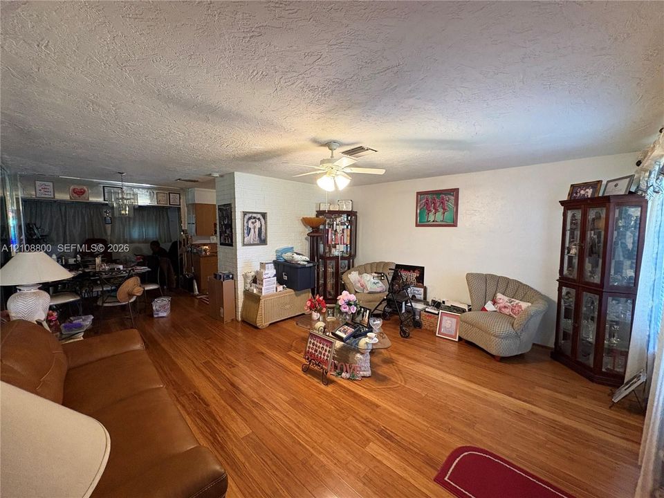 Living area featuring wood-finish flooring, a ceiling fan, and a textured ceiling finish