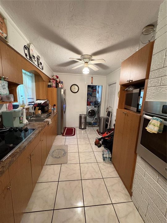 Kitchen featuring wood cabinetry, integrated oven, stone-patterned countertops, tile flooring, and a ceiling-mounted light fixture