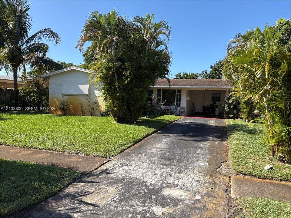 Single-story exterior featuring a covered front entry, asphalt driveway, and mature landscaping