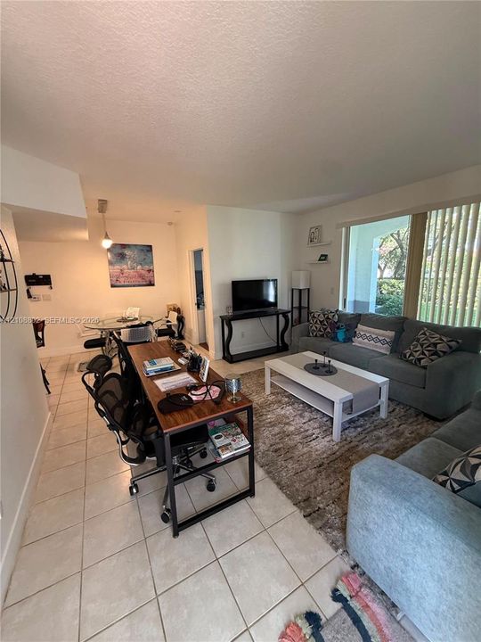 Interior space featuring large-format tile flooring, recessed lighting, neutral wall paint, and floor-to-ceiling windows with vertical blinds