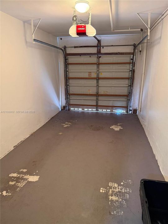 Single-car garage featuring a sectional overhead door and an integrated automatic garage door opener