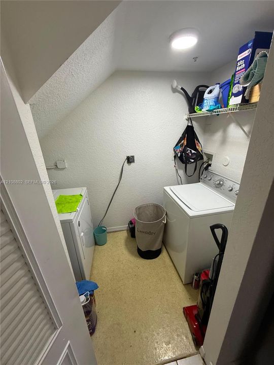 Laundry area featuring a sloped ceiling, wall-mounted wire shelving, and overhead flush-mount lighting