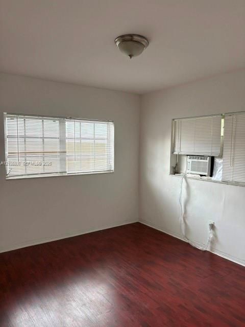 Room featuring wood-finish flooring, white walls, dual windows, and a flush-mount ceiling light fixture