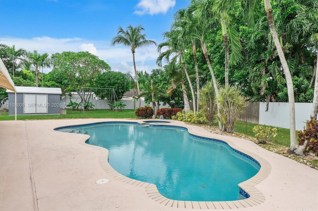 Exterior featuring a covered patio, swimming pool, integrated spa, and siding finish
