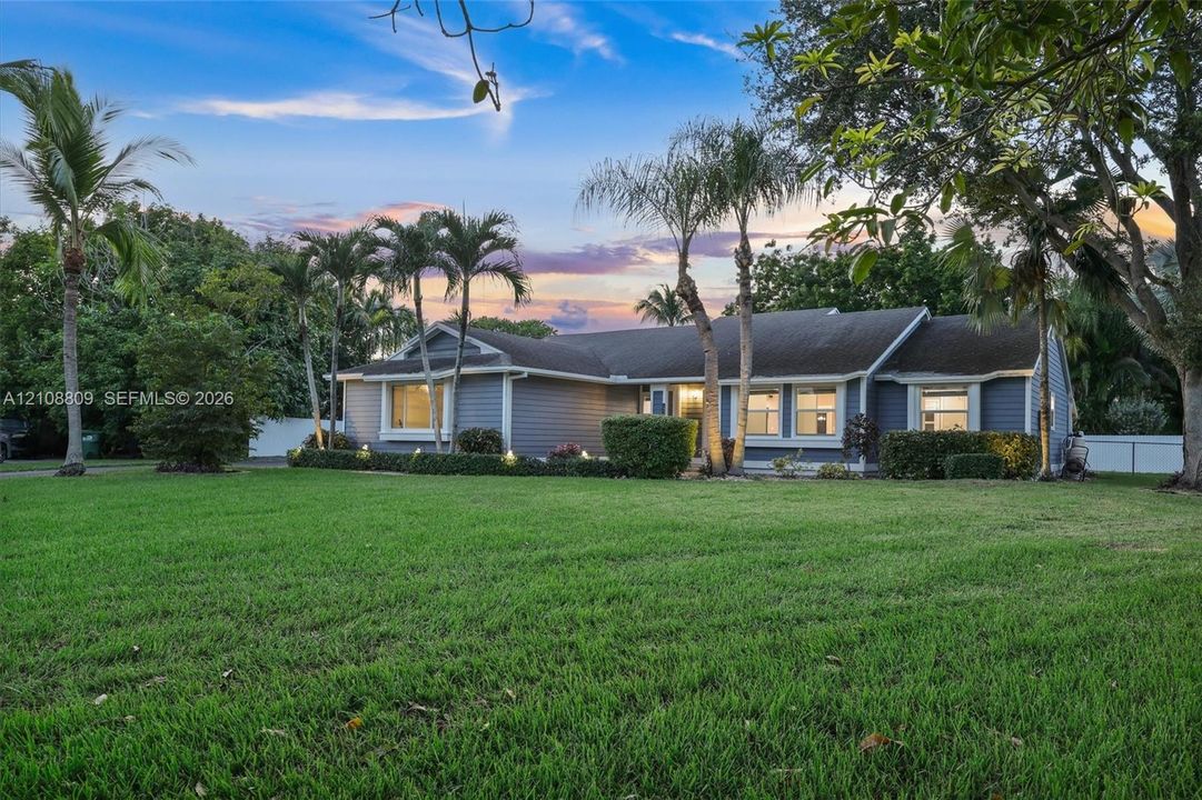 Single-story residence featuring horizontal lap siding, a shingled roof, multi-pane windows, and extensive mature landscaping