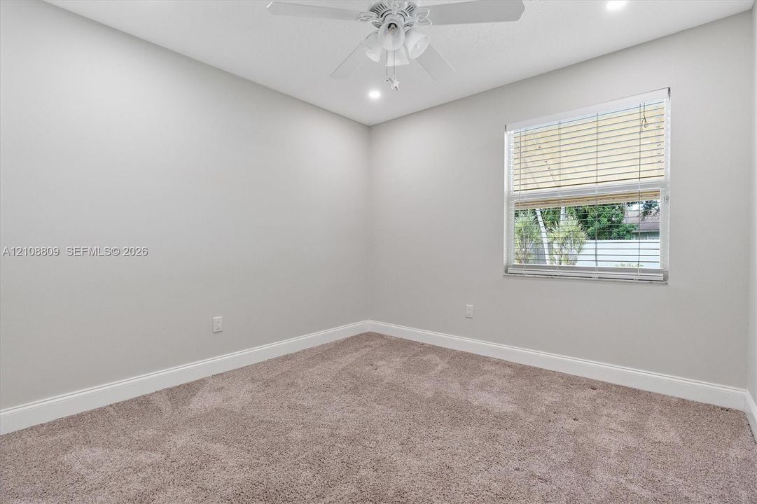 Neutral interior space featuring wall-to-wall carpeting, a ceiling fan with integrated lighting, recessed lighting, and a window with horizontal blinds