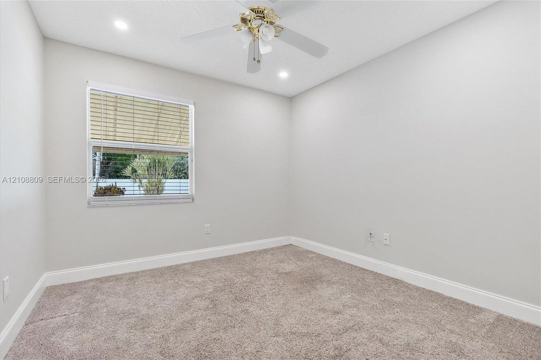 Neutral-toned interior space featuring wall-to-wall carpeting, a single-hung window, and a ceiling fan with integrated lighting