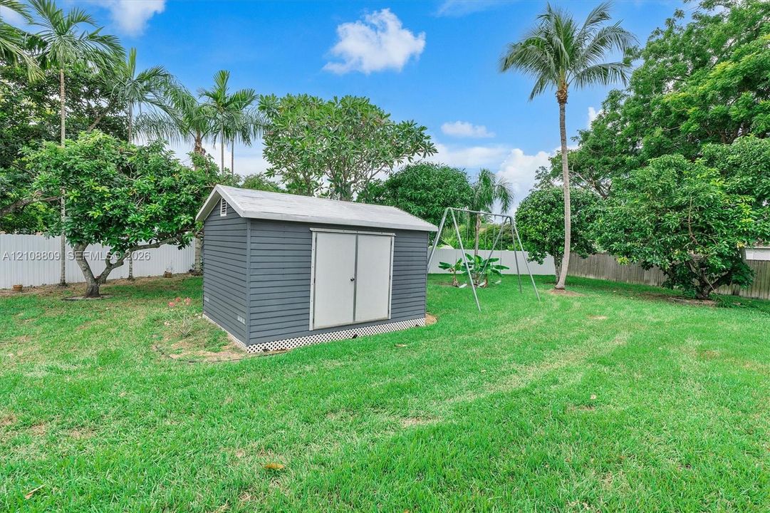 Backyard featuring an in-ground swimming pool, expansive covered patio, and detached storage structure