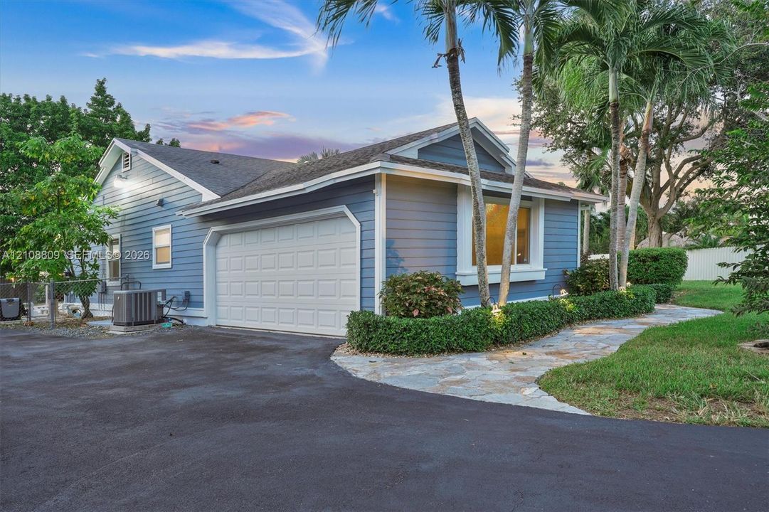 Rear yard featuring a dark gray storage shed with a gabled roof, white vinyl perimeter fencing, and mature landscaping