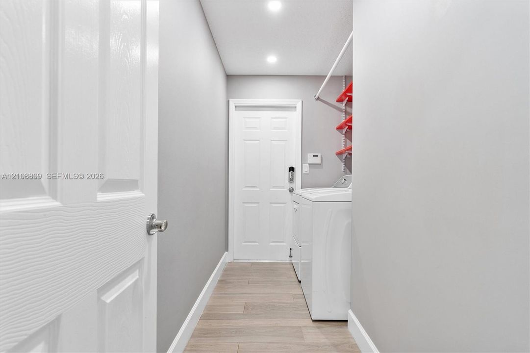 Laundry area featuring wood-finish flooring, recessed lighting, and a six-panel interior door