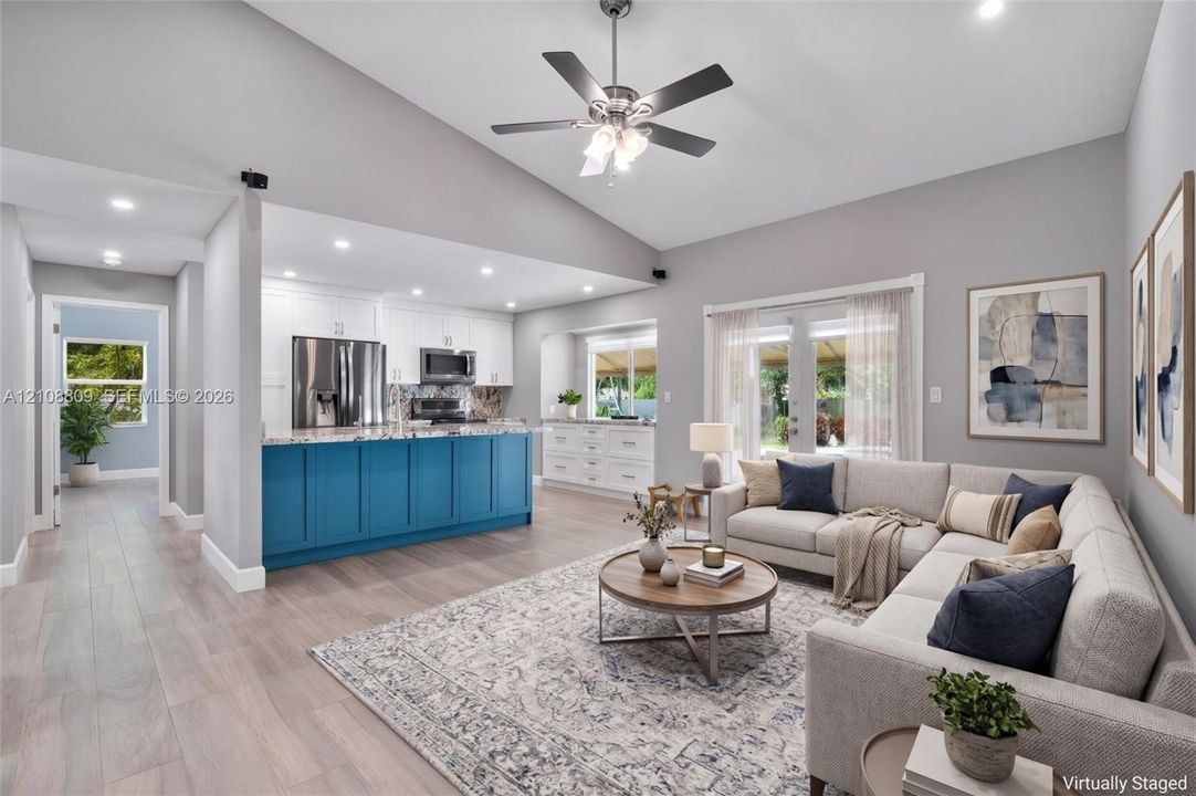 Vaulted ceilings, wood-finish flooring, recessed lighting, central kitchen island with cabinetry, and double glass doors