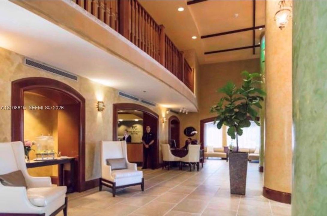 Two-story open foyer featuring arched doorways, stone-tile flooring, decorative wood-finish railings, and recessed ceiling lighting