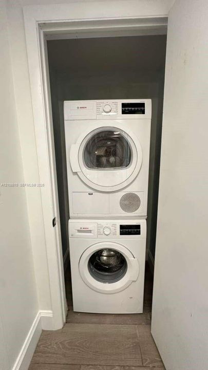 Stacked Bosch front-load washer and dryer set situated within a dedicated closet featuring neutral-toned tile flooring