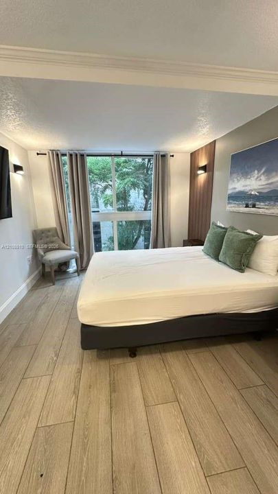 Wood-finish flooring, floor-to-ceiling windows, vertical wood-panel accent wall, and wall-mounted sconce lighting
