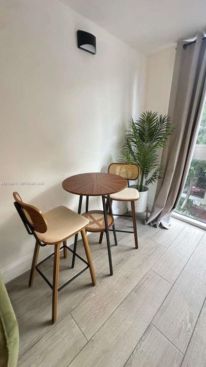Wood-finish plank flooring, wall-mounted semi-circular light fixture, and floor-to-ceiling glass window
