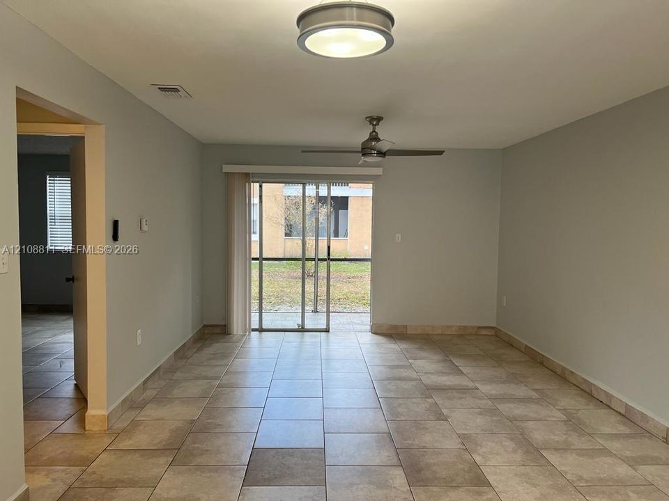Neutral-toned ceramic tile flooring, sliding glass door, brushed nickel ceiling fan, and flush-mount circular ceiling lighting