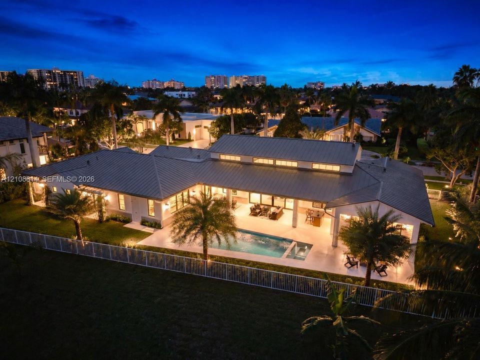 Single-story residence featuring a metal roof, clerestory windows, an expansive covered patio, a rectangular swimming pool, and a fenced perimeter