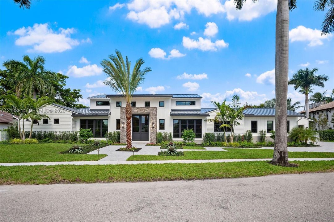 Contemporary residence featuring a clean-lined facade, multi-level roofline with metal roofing, stone veneer accent at the entryway, and expansive windows