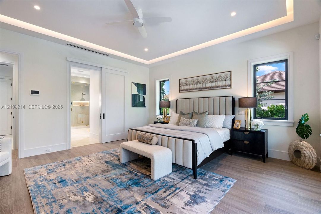 Tray ceiling with recessed lighting, porcelain-finish flooring, sliding interior door, and multi-pane windows with dark framing