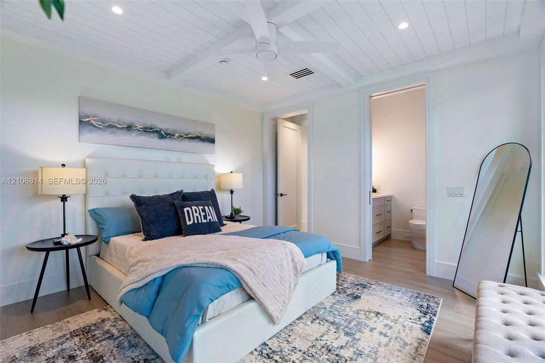 Beadboard ceiling with crown molding, recessed lighting, and a central ceiling fan, featuring porcelain-finish flooring and a multi-panel door