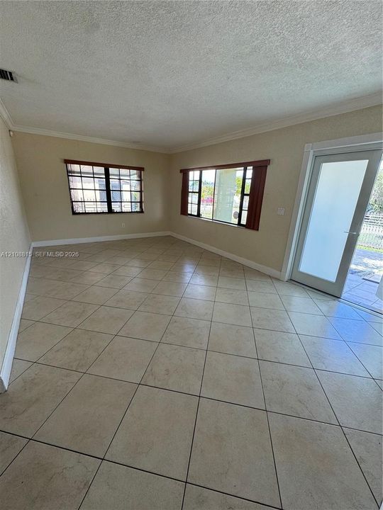 Interior space featuring large-format diagonal tile flooring, dual windows with dark-finish frames, and a glass-paneled exterior door