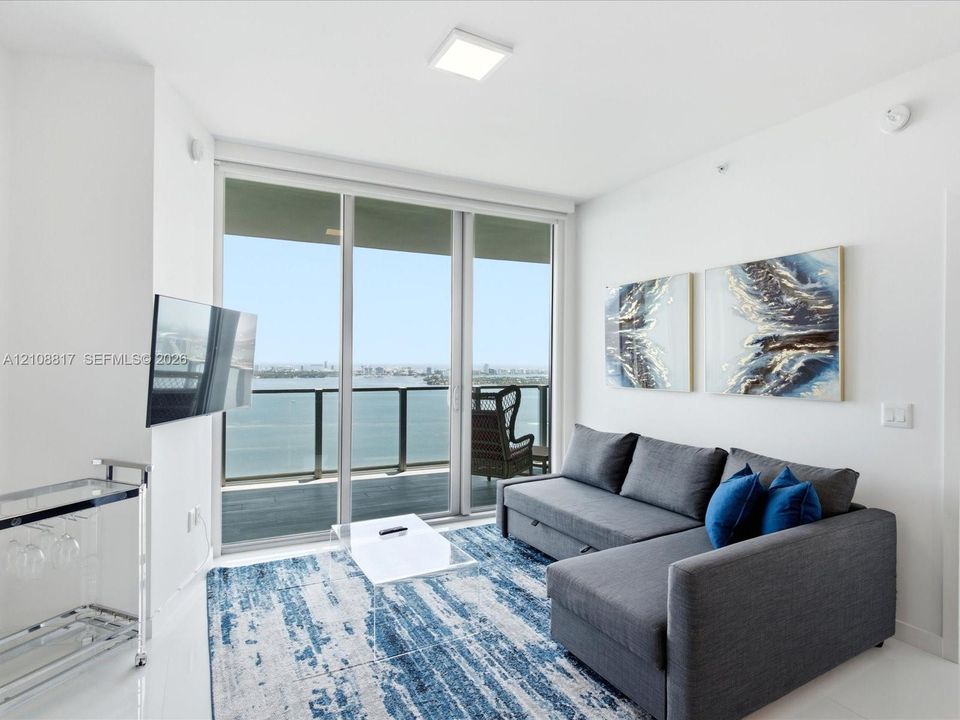 Floor-to-ceiling sliding glass door, private balcony with metal railing, and neutral flooring