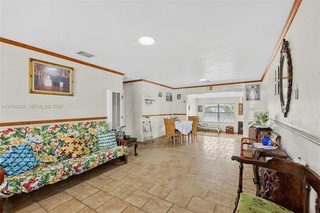Open-concept interior featuring light-toned tile flooring, chair rail molding, and recessed ceiling lighting