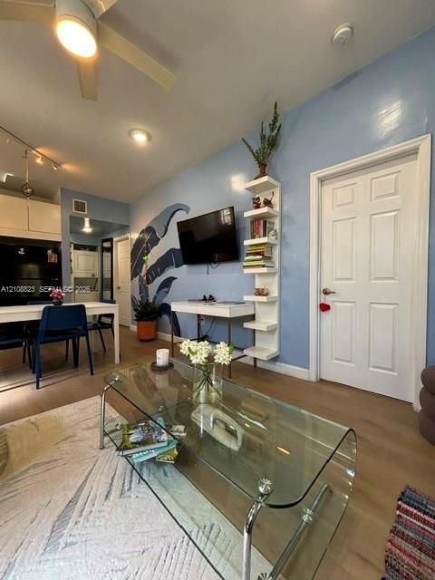 Wood-finish flooring, white built-in wall shelving, ceiling fan with integrated lighting, and recessed ceiling lights