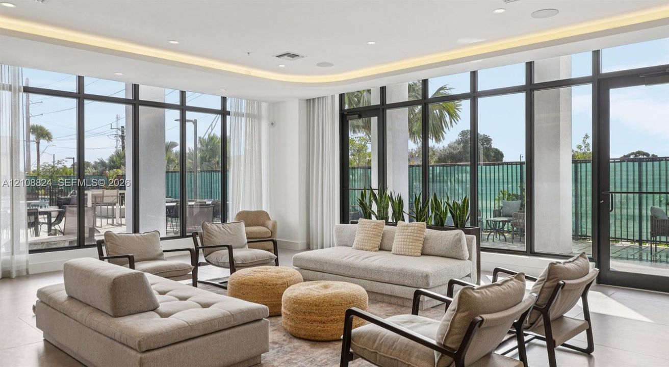 Open-concept space featuring floor-to-ceiling windows, recessed cove lighting, sleek tile flooring, and metal-framed exterior access doors
