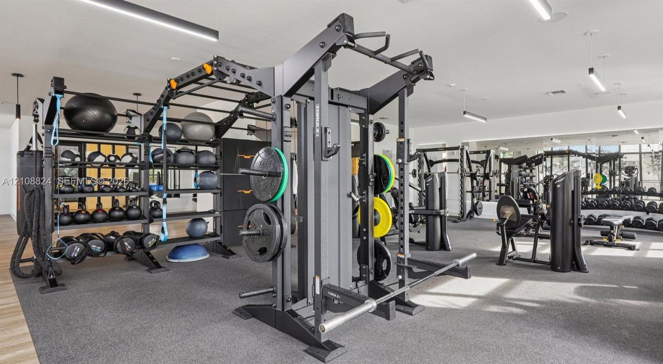 Fitness facility featuring wall-to-wall mirrors, recessed linear lighting, rubberized flooring, and integrated built-in equipment storage