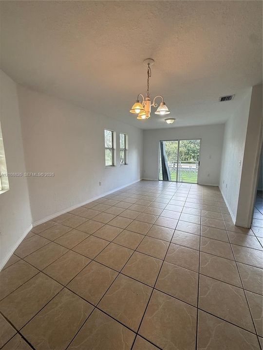 Interior space featuring neutral tile flooring, a multi-arm chandelier, recessed ceiling lighting, and sliding glass doors