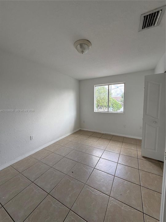 Room featuring neutral tile flooring, a single-pane window, and a white interior door