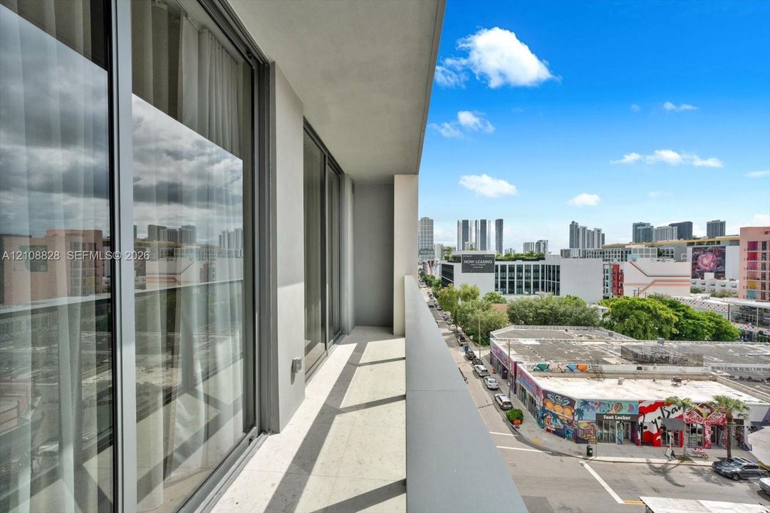 Private covered balcony featuring neutral tile flooring, floor-to-ceiling glass doors, and a sleek metal railing