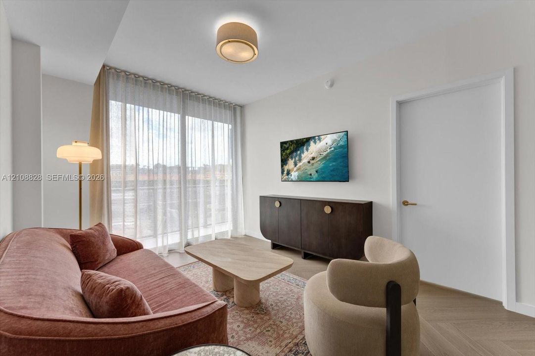 Floor-to-ceiling glass sliding doors, wood-finish flooring in a herringbone pattern, drum-style flush mount ceiling light, and clean-lined interior finishes