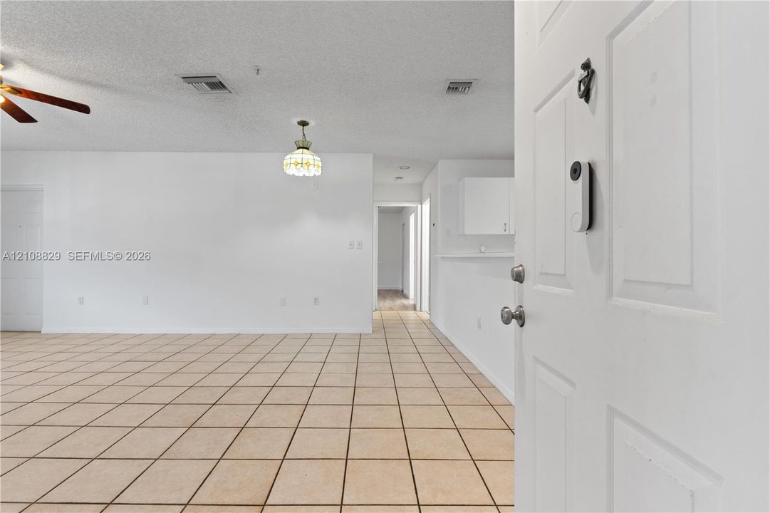 Interior featuring square ceramic floor tiling, ceiling fan with light kit, pendant lighting, and neutral wall tones