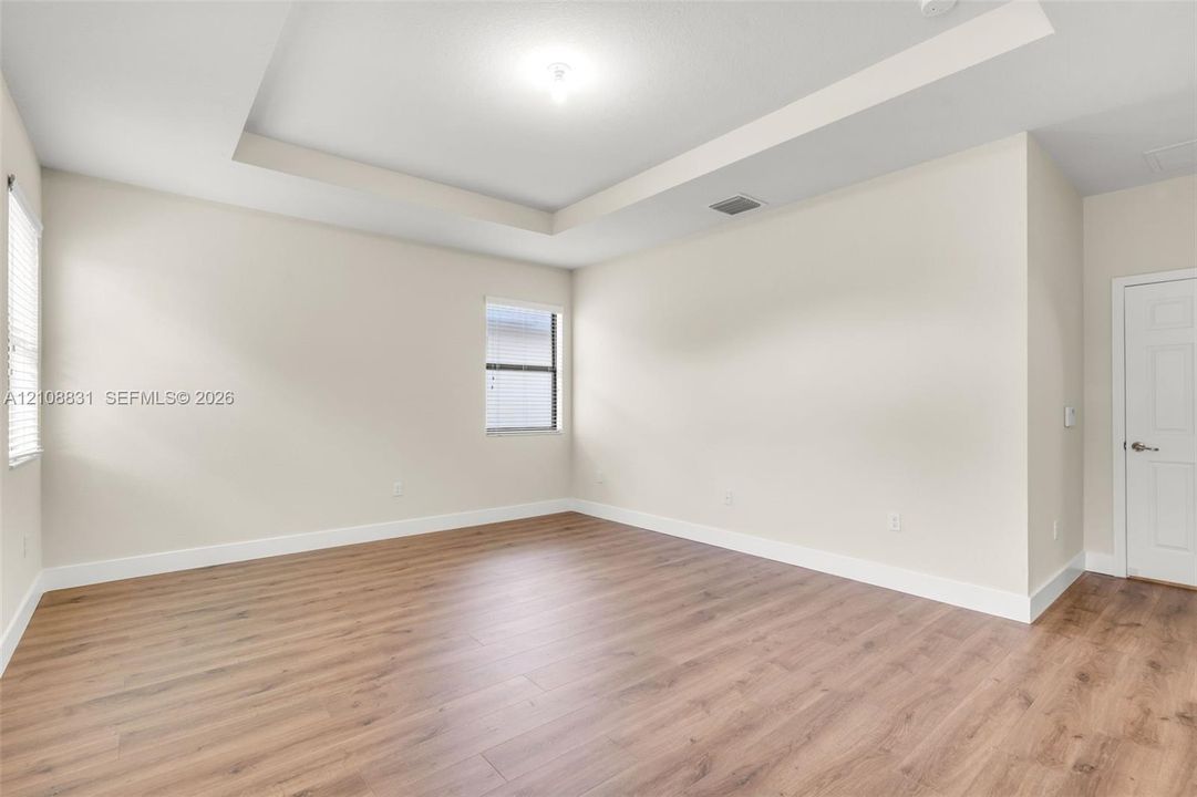 Interior space featuring a recessed tray ceiling, wood-finish flooring, and a single-panel interior door