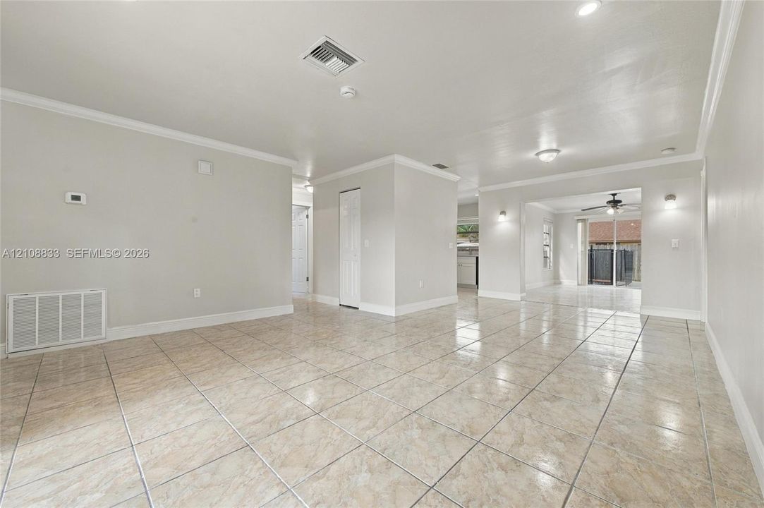 Interior space featuring neutral wall paint, tile flooring, recessed ceiling lighting, and crown molding