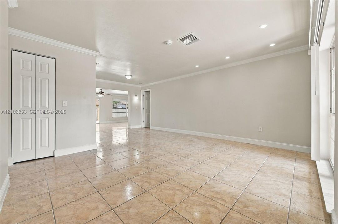 Interior room featuring neutral wall paint, recessed lighting, crown molding, tile flooring, and a closet with paneled doors