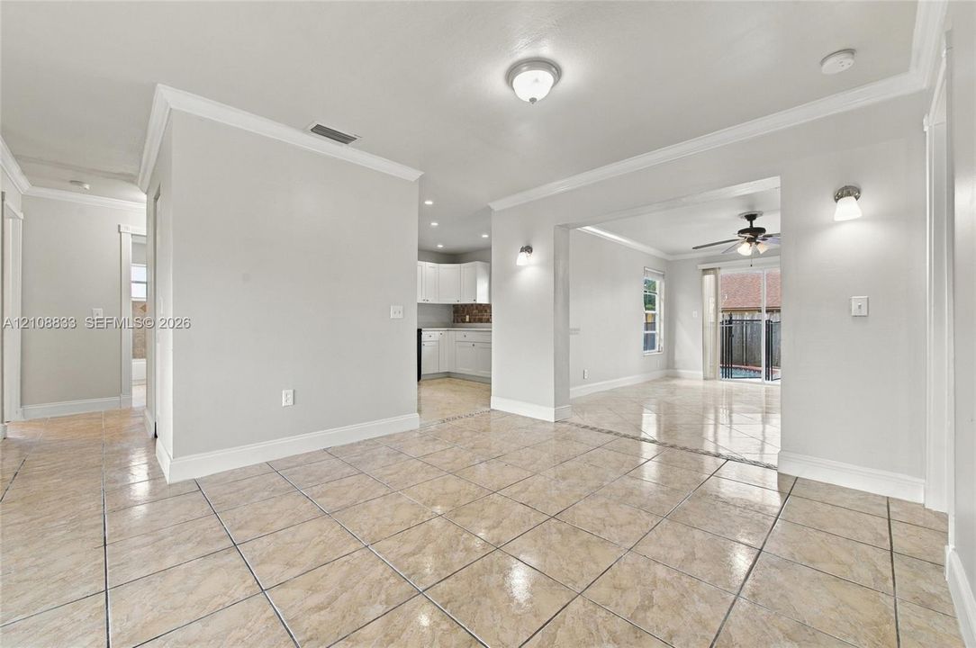 Interior featuring large-format tile flooring, crown molding, wall-mounted light fixtures, and a glass sliding door