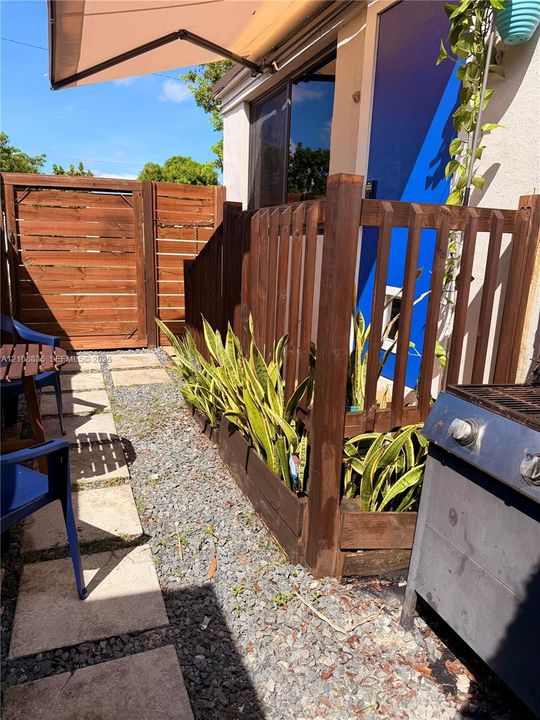 Outdoor patio featuring wood-slat privacy fencing, concrete pavers, crushed stone surfacing, and built-in wood planters