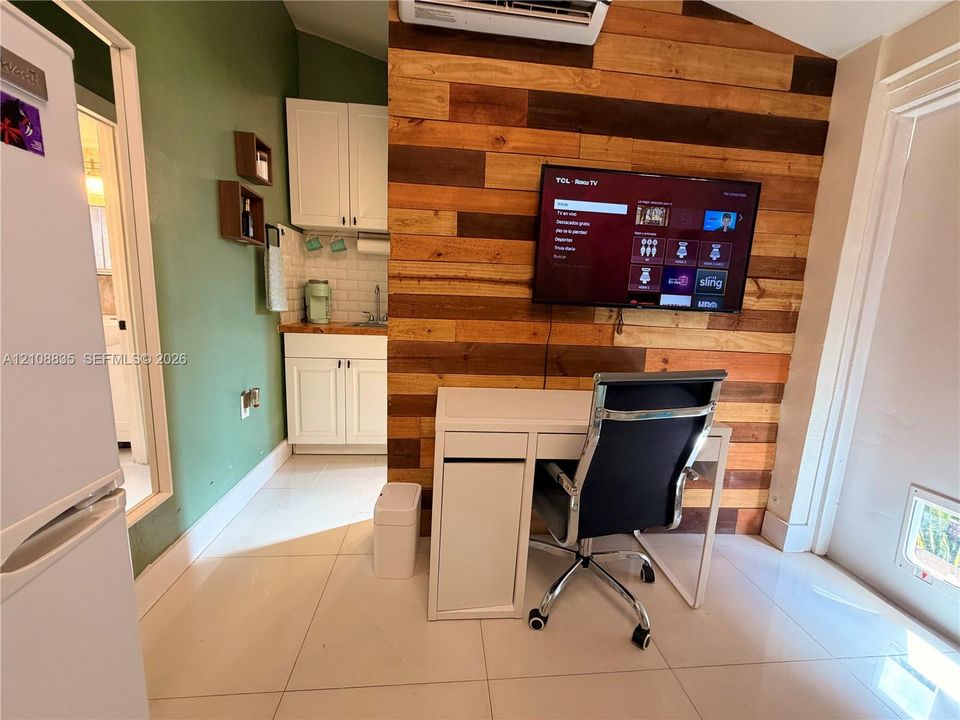 Accent wall featuring natural wood-finish planking, white cabinetry, tile backsplash, and light-toned tile flooring