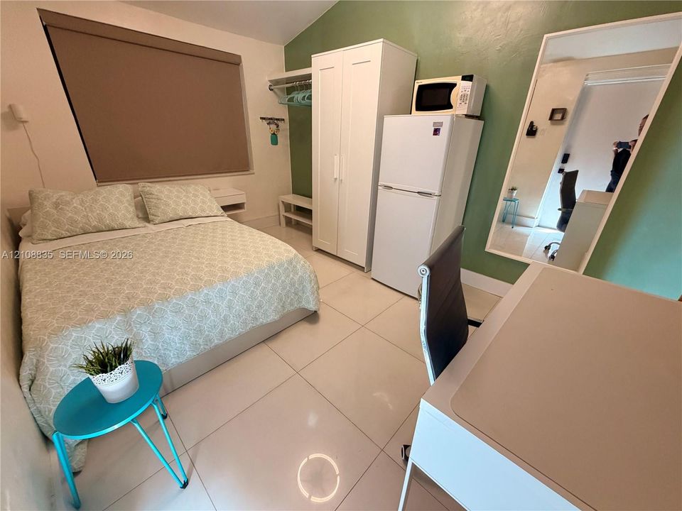 Neutral-tone ceramic tile flooring, painted accent wall, and a large-format wall mirror